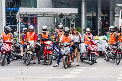 Bangkok, Thailand - September 25th 2012: A young Thai girl climbs onto the back of a motorcycle taxi. This form of transport is popular.