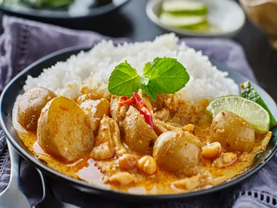 thai massaman curry on plate with jasmine rice and lime wedge